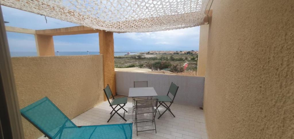 a balcony with a table and chairs and a view of the ocean at Très joli studio 4 personnes avec terrasse front de mer in Leucate
