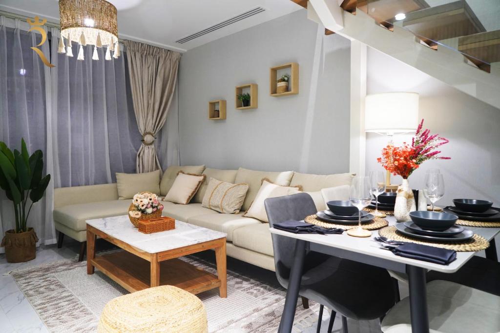 un soggiorno con divano e tavolo di 2BR SkyHome at Jade Masdar Oasis a Al Qurayyah