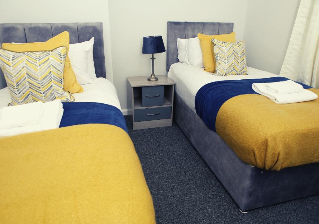 twee bedden in een kamer met geel en blauw bij Must stay 3 Bedroom house near Greenwich and Blackheath- Ideal for families and contractors in Londen