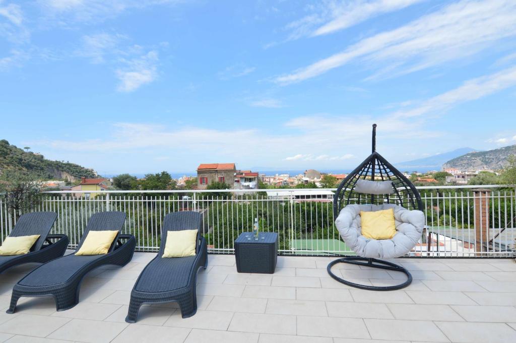 eine Terrasse mit Stühlen und Tischen auf dem Balkon in der Unterkunft La Terrazza Family Holidays, Sorrento Coast in Sant'Agnello