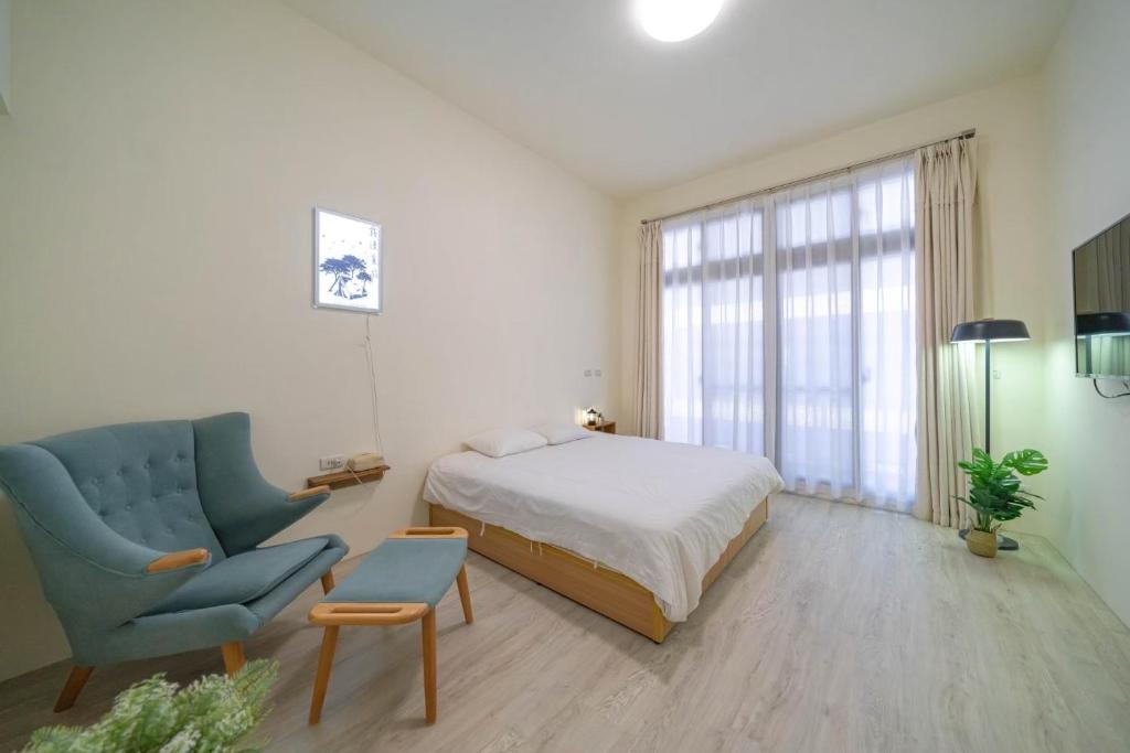 een slaapkamer met een bed en een blauwe stoel bij 路邊覓宿 in Guilin