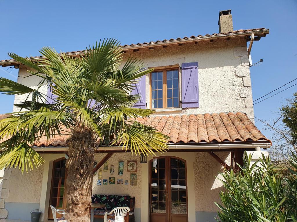 a house with a palm tree in front of it at Le Presbytère in Saint-Romain