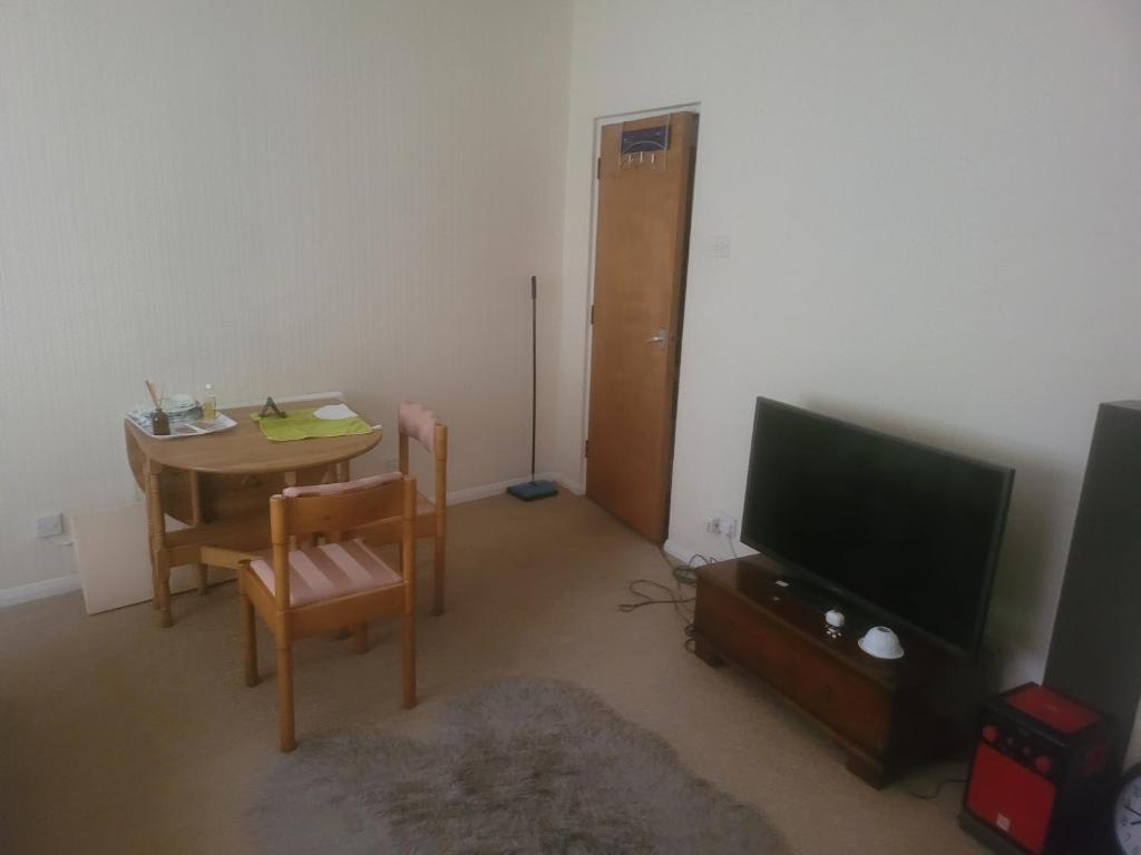 a living room with a table and a television at Pent flat in Northampton