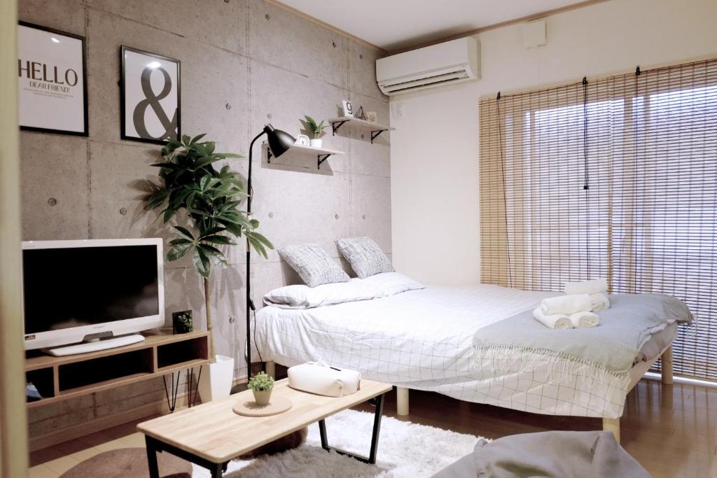 ein Schlafzimmer mit einem Bett, einem Fernseher und einem Tisch in der Unterkunft Daiichi Mitsumi Corporation - Vacation STAY 15232 in Musashino