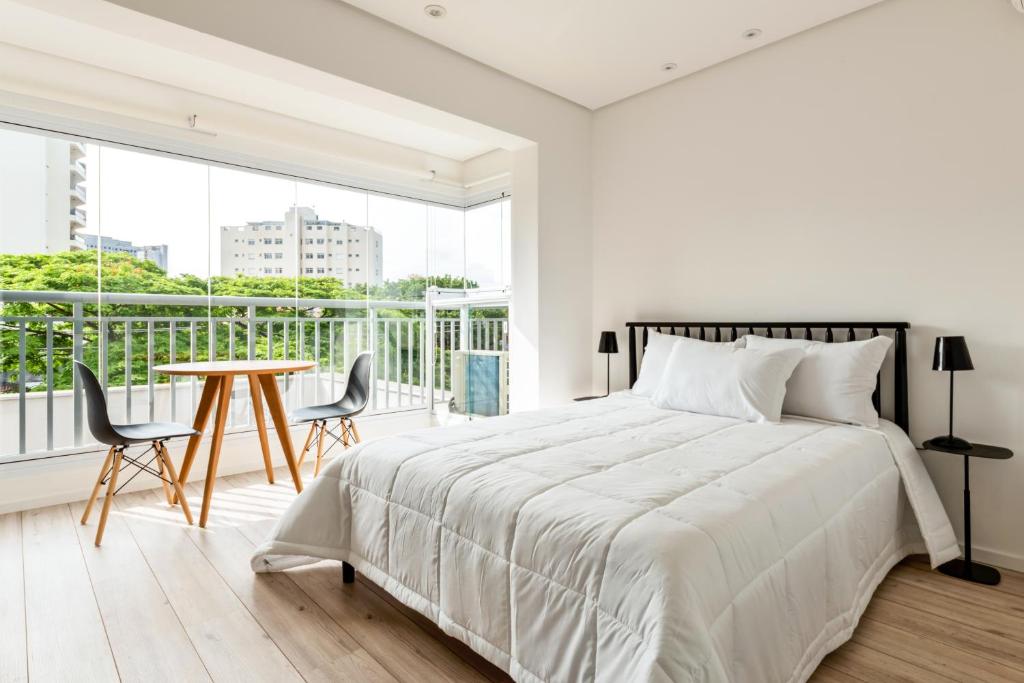 a white bedroom with a bed and a table at Tabas - Edifício Walk SP in São Paulo