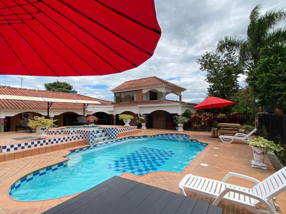 een zwembad met een rode parasol en een huis bij finca vacacional villa el Resplandor in Dujos