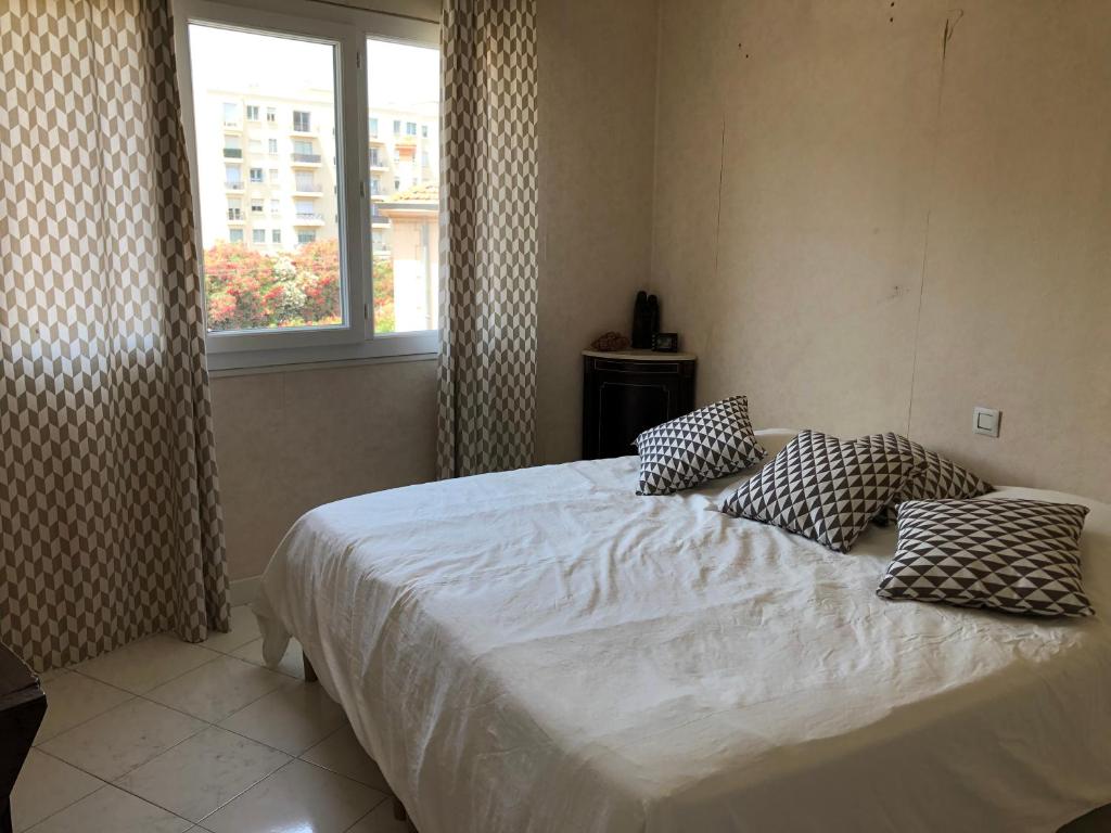 ein Schlafzimmer mit einem Bett mit Kissen und einem Fenster in der Unterkunft Appartement chaleureux proche de la croisette in Cannes