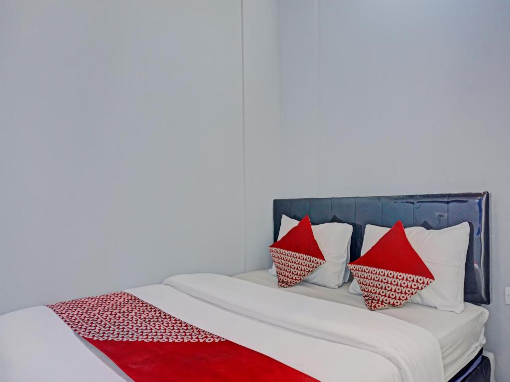 ein Bett mit roten und weißen Kissen darauf in der Unterkunft Capital O 92765 J&b Smart Sentul in Bogor