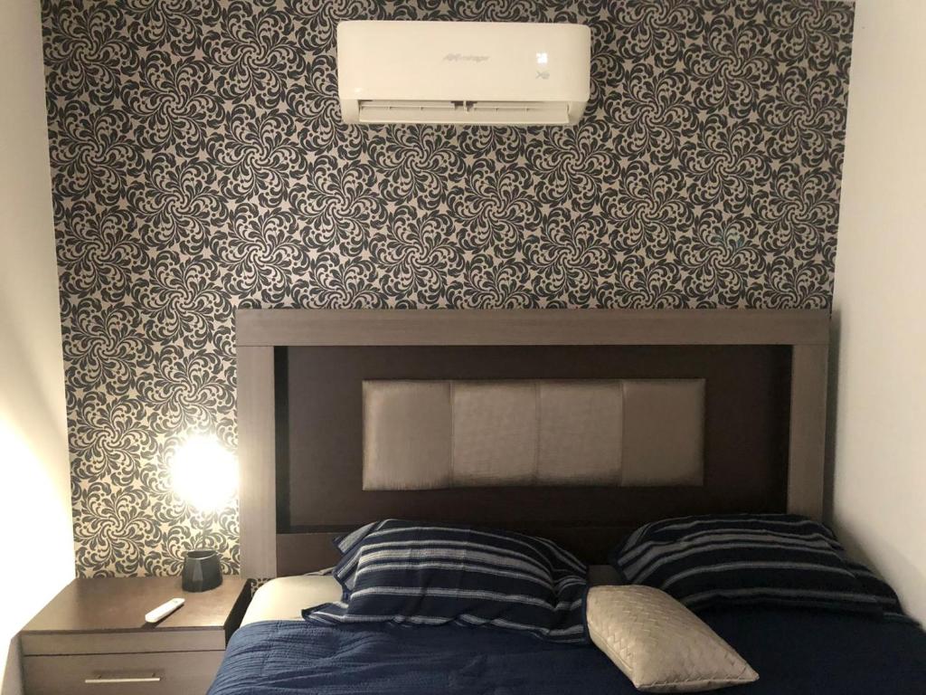 um quarto com uma cama com uma cabeceira e uma parede em La casa azul em Culiacán