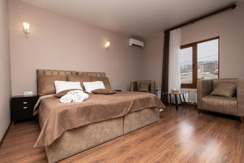 Hillside Guest House في يريفان: غرفة نوم بسرير كبير وكرسي