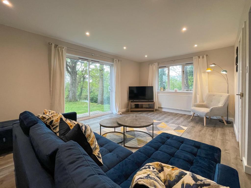 sala de estar con sofá azul y TV en Surrey Hills Lodge, en Ewhurst
