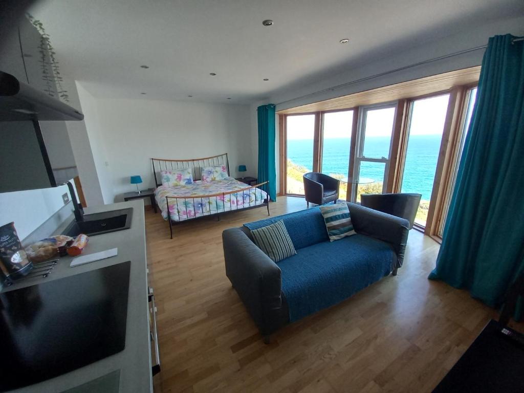 a living room with a blue couch and a bed at CELLAR COVE in Perranporth