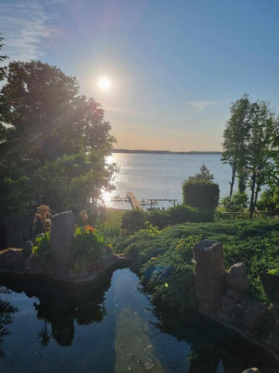 a view of a pond with the sun setting over the water at Domek Letniskowy Monika in Jeziorowskie