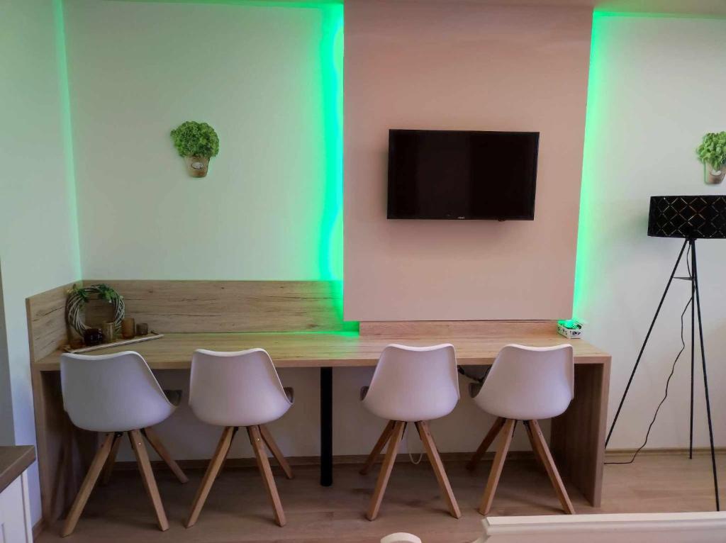 stół z 4 białymi krzesłami i telewizor na ścianie w obiekcie Mountain view apartments w mieście Bad Mitterndorf