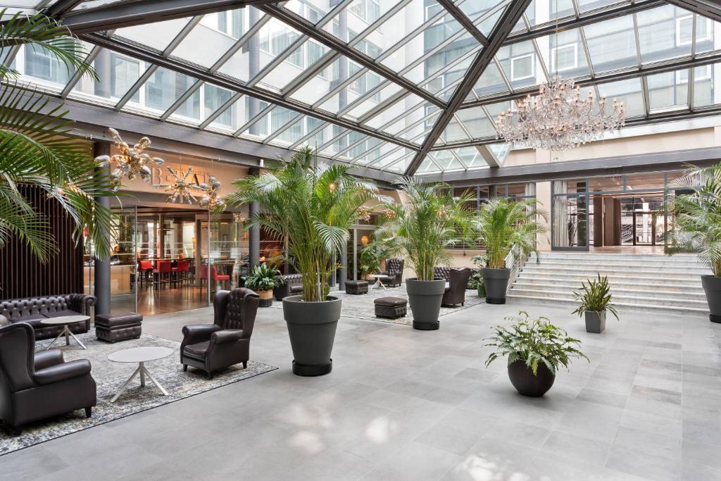 hol z palmami i krzesłami oraz żyrandolem w obiekcie Four Points Sheraton Bolzano Bozen w mieście Bolzano
