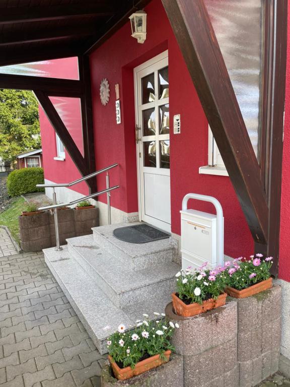 ein rotes Haus mit Blumen davor in der Unterkunft Visit_Oberhof_2 in Oberhof