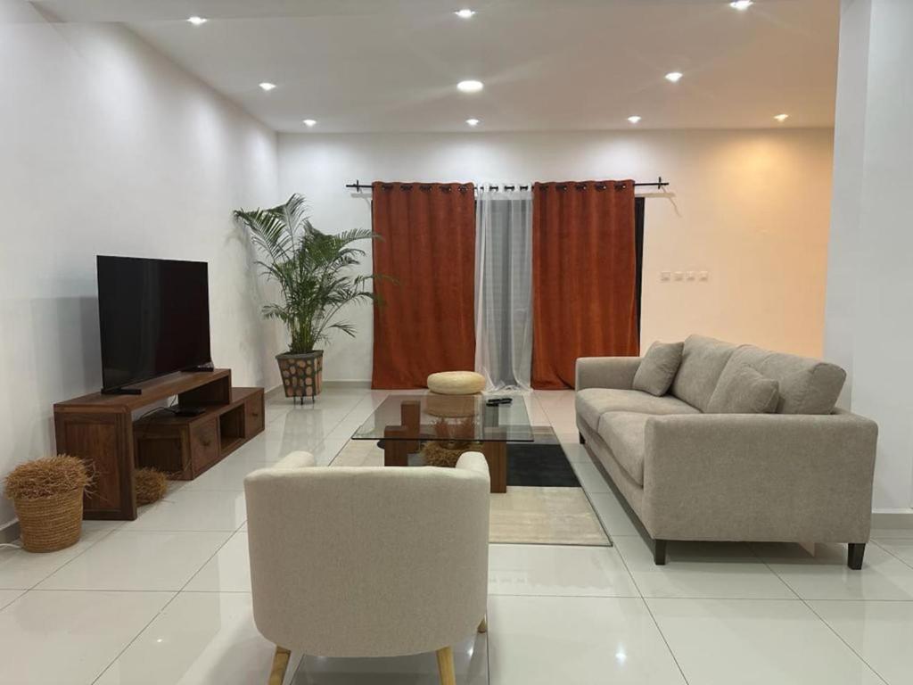 a living room with a couch and a tv at Villa d'exception à 20 min de l'aéroport 