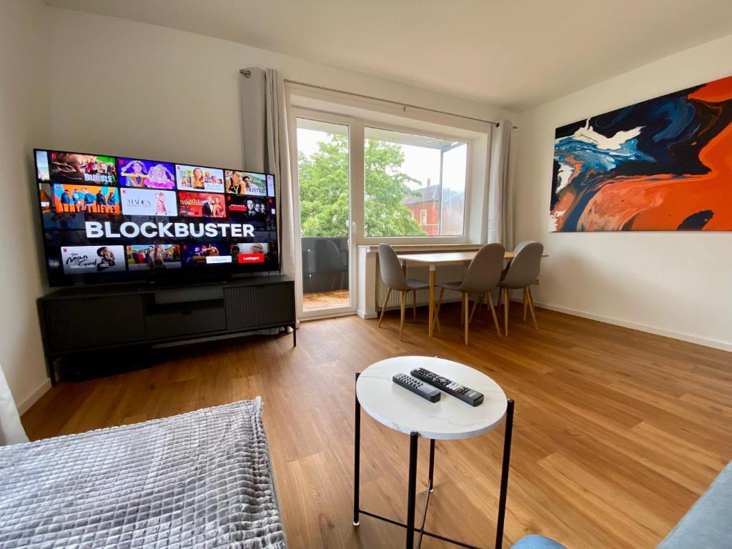 uma sala de estar com televisão e uma mesa com cadeiras em LEMON - 4 Per - Garage - 65 Zoll em Braunschweig