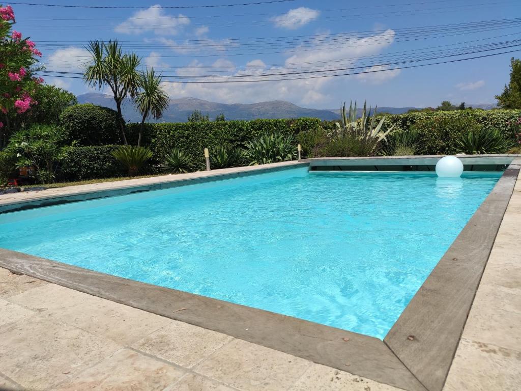 una piscina con acqua blu in un cortile di Superbe villa de charme avec piscine chauffée a Roquefort-les-Pins