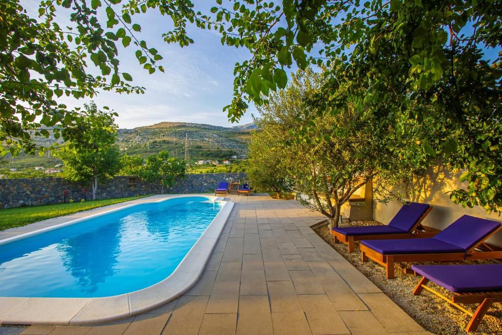 una piscina con sedie a sdraio e alberi viola di Villa Leandra near Omiš, private pool a Tugare