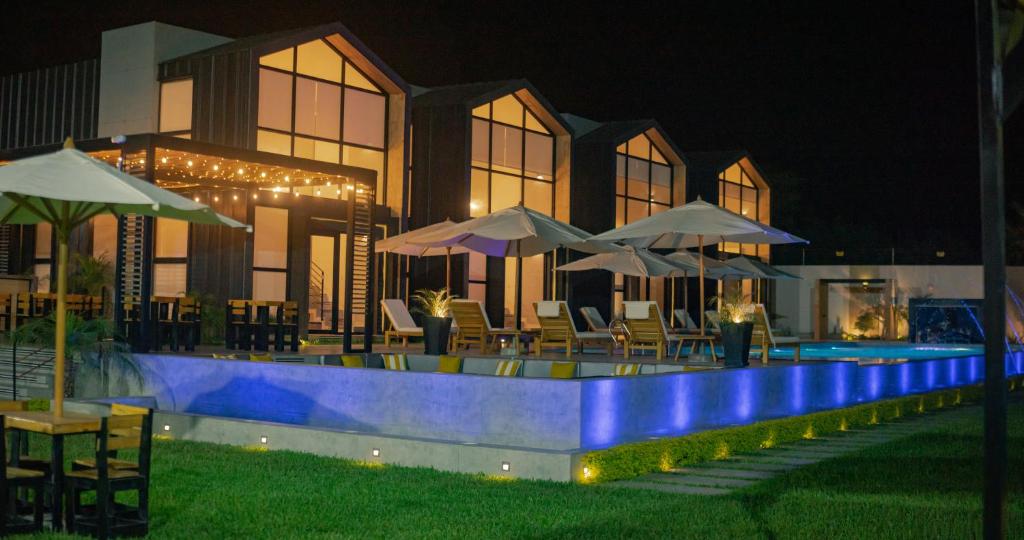 a swimming pool with chairs and umbrellas at night at Awqa Loft & Camp in Trujillo