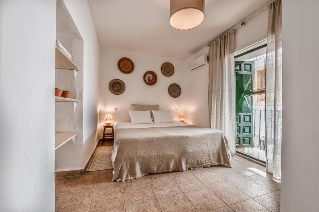 a white bedroom with a bed and a window at Encanto Guesthouse in Canillas de Aceituno