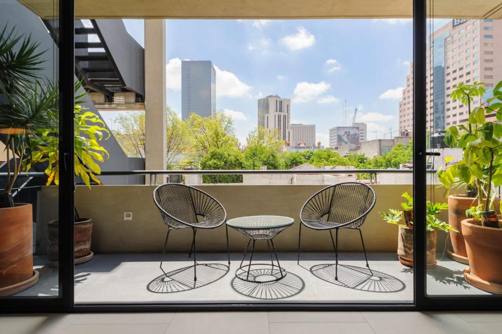 Un balcón con dos sillas y una mesa. en Unique 1BR in Cuauhtémoc, en Ciudad de México