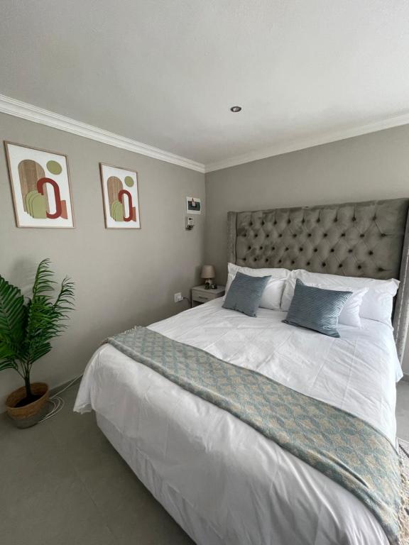 een slaapkamer met een groot wit bed met blauwe kussens bij Spacious stay-in bachelor apartment in Kempton Park