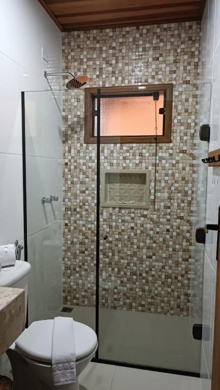 um banheiro com vaso sanitário e chuveiro de vidro em Pousada Estrelícia em Cunha