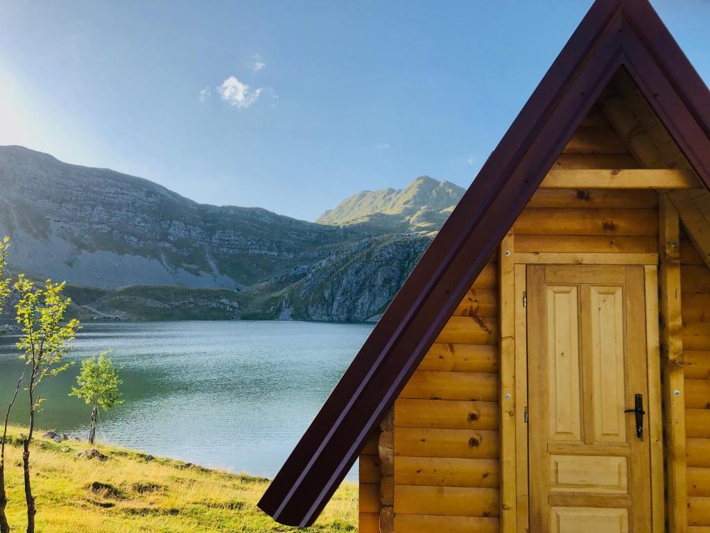 een houten hut met een deur voor een meer bij Kapetanovo Jezero Bungalov in Podgorica