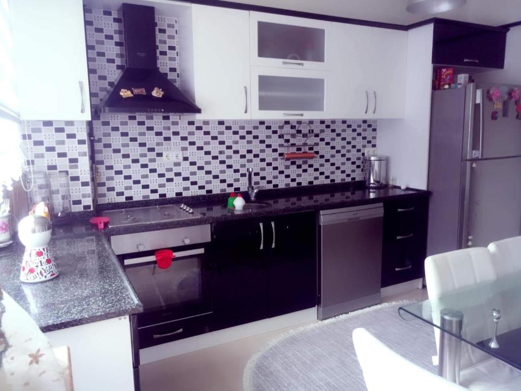 una cucina con banconi neri e frigorifero di Ultra lüks eşyalı kiralık daire a Of