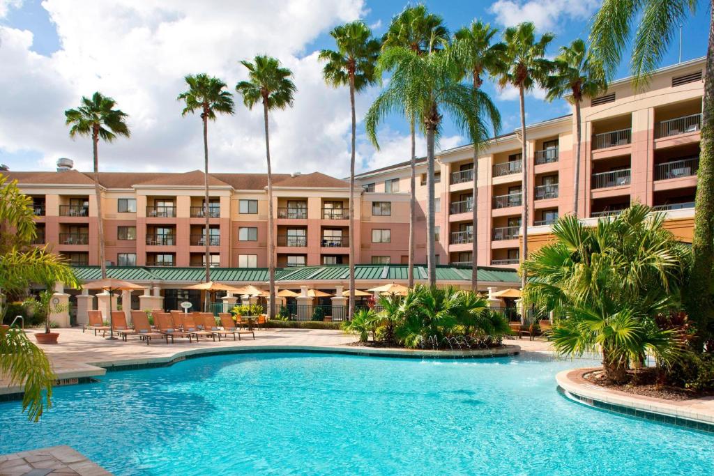 una vista exterior del complejo con una piscina y palmeras en Courtyard by Marriott Orlando Lake Buena Vista in the Marriott Village, en Orlando