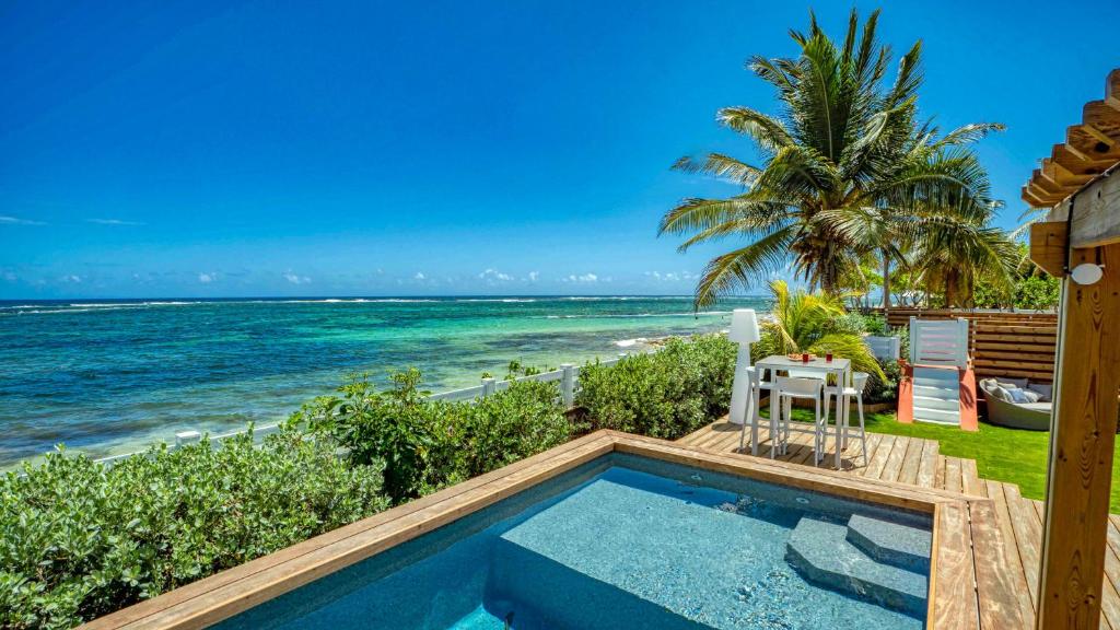 een zwembad met uitzicht op het strand bij Villa pieds dans l'eau avec accès plage - GPMO13 in Le Moule