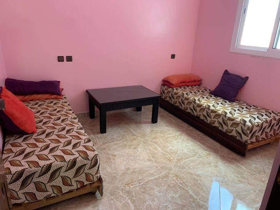 a room with two beds and a table in it at Bienvenue chez Walid in Larache