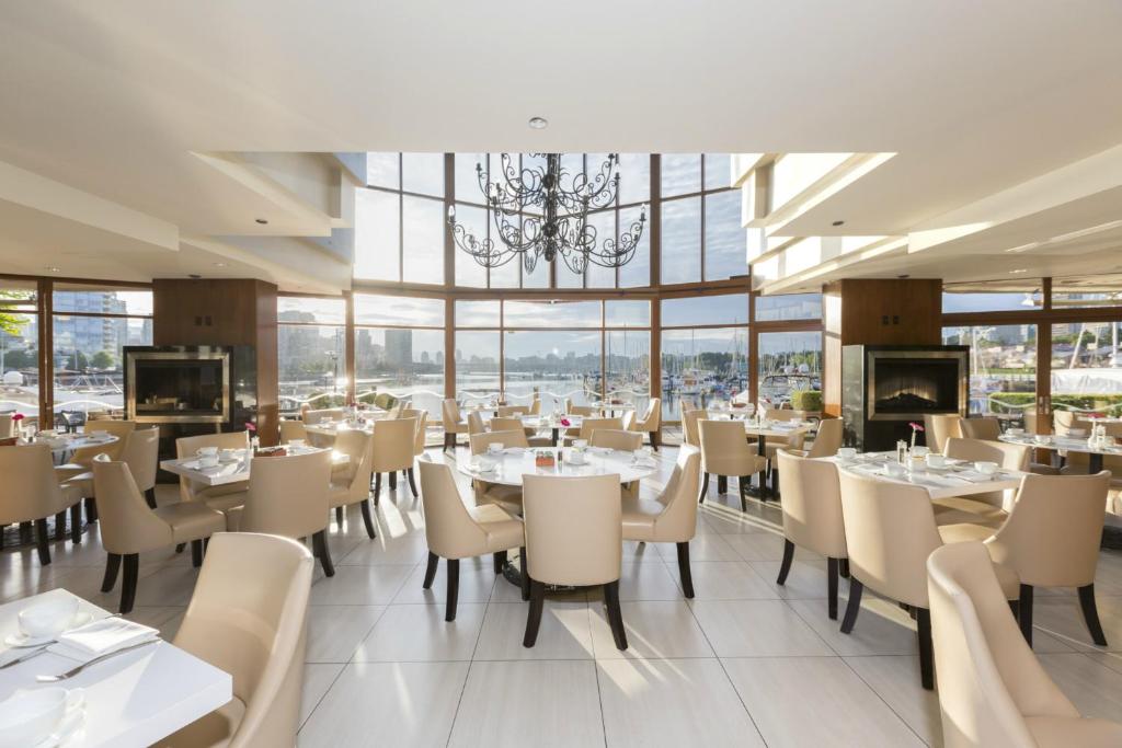 a restaurant with tables and chairs and a chandelier at Granville Island Hotel in Vancouver