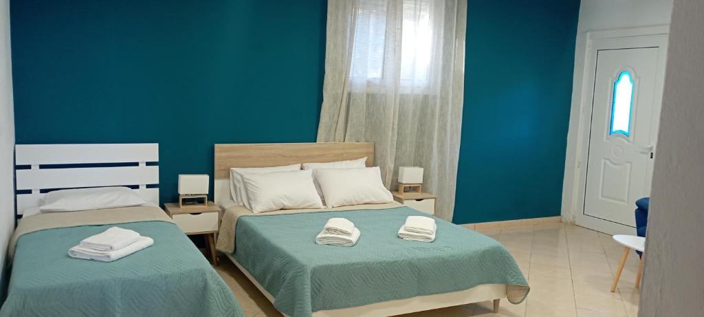 a bedroom with two beds with blue walls and a window at Lentas Royal in Lentas