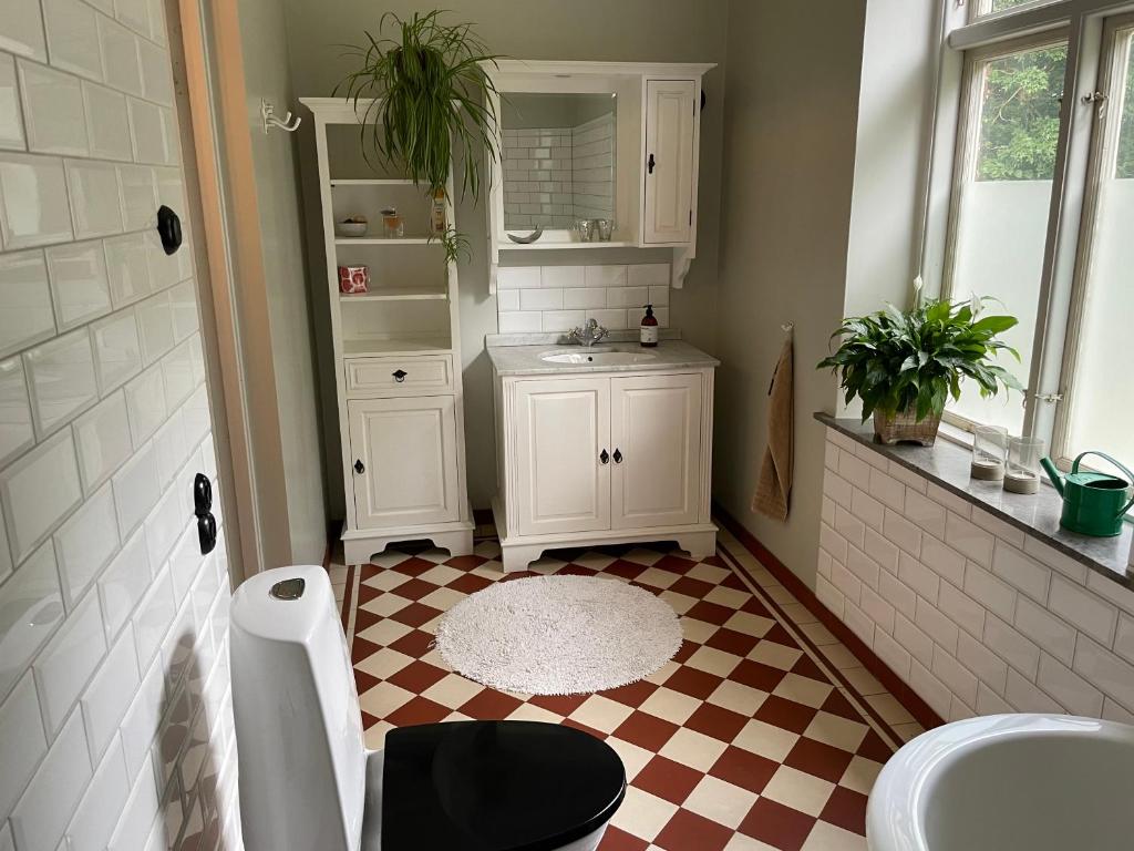 a bathroom with a checkered floor and a sink at Rum på Gårdstånga Prästgård in Flyinge