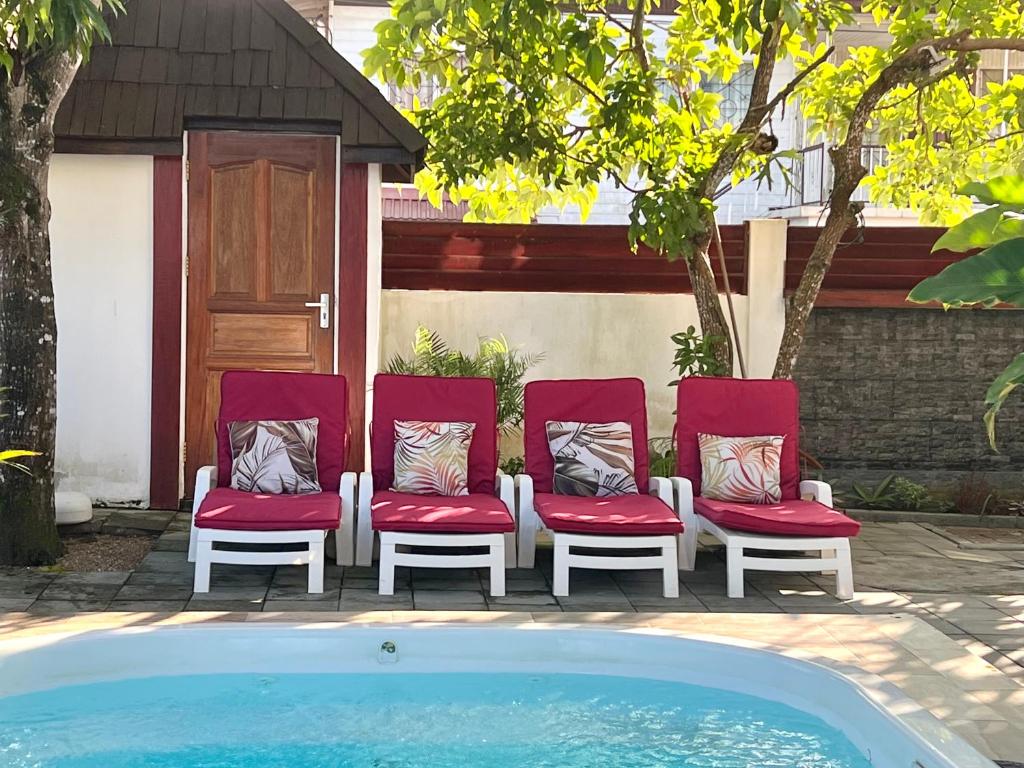 a group of red chairs sitting next to a pool at Villa Famiri Boutique hotel in Paramaribo