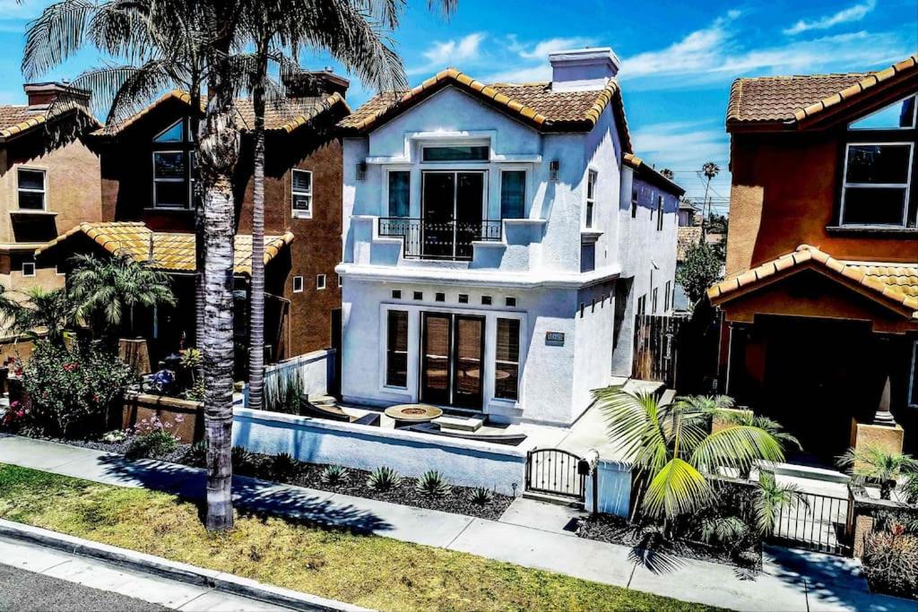 una casa blanca con una palmera delante de ella en The White Beach House of Huntington, en Huntington Beach