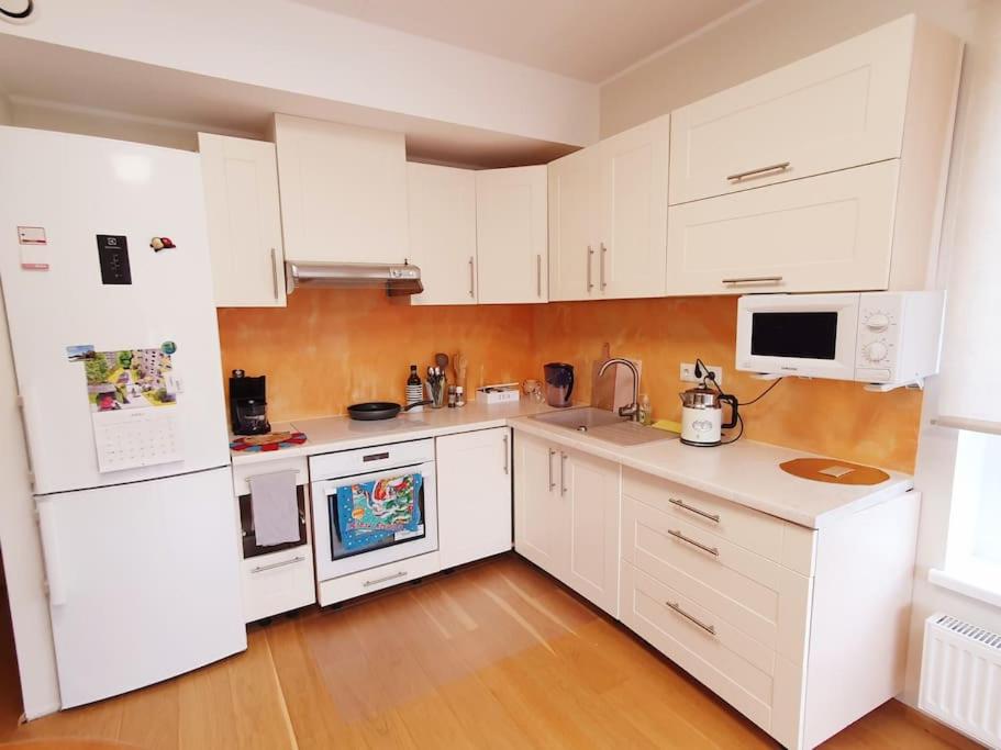 a kitchen with white cabinets and white appliances at Bright 3-room apartment in Mustamäe in Tallinn