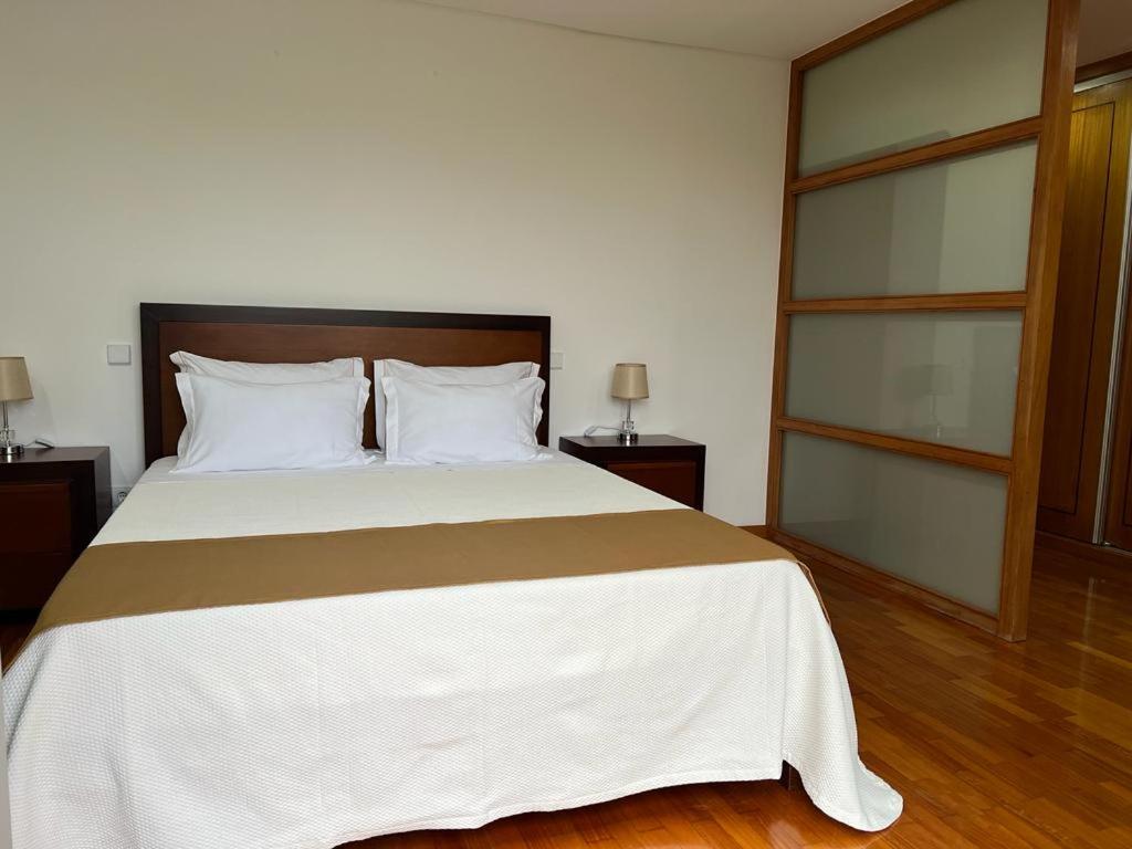 a bedroom with a large bed with white and brown sheets at CasaAnabela in Póvoa de Varzim