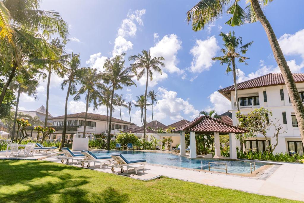 un complejo con piscina y palmeras en Legong Keraton Beach Hotel en Canggu