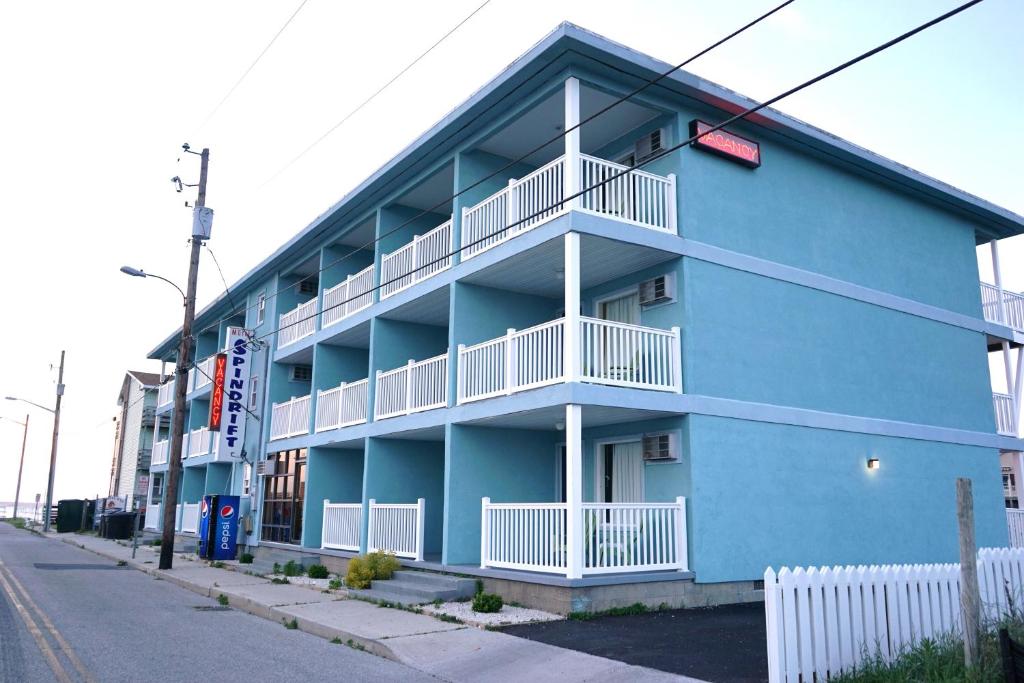 a blue building with white balconies on a street at Spindrift Motel in Ocean City