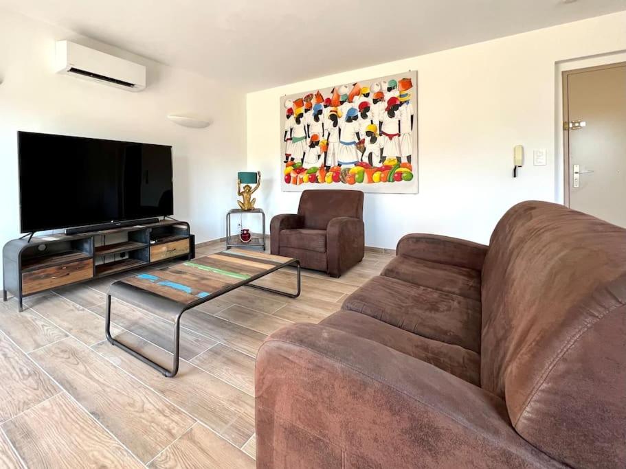 a living room with a couch and a flat screen tv at Le Saint-Jalmes P2 + Parking in Nîmes