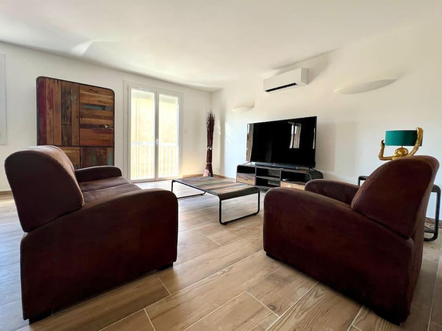 a living room with two couches and a flat screen tv at Le Saint-Jalmes P2 + Parking in Nîmes