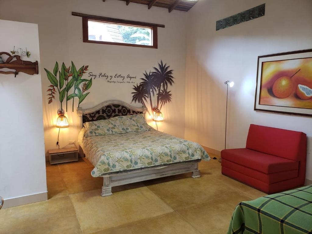 een slaapkamer met een bed en een rode stoel bij Villa Nico hospedaje campestre in Bochalema