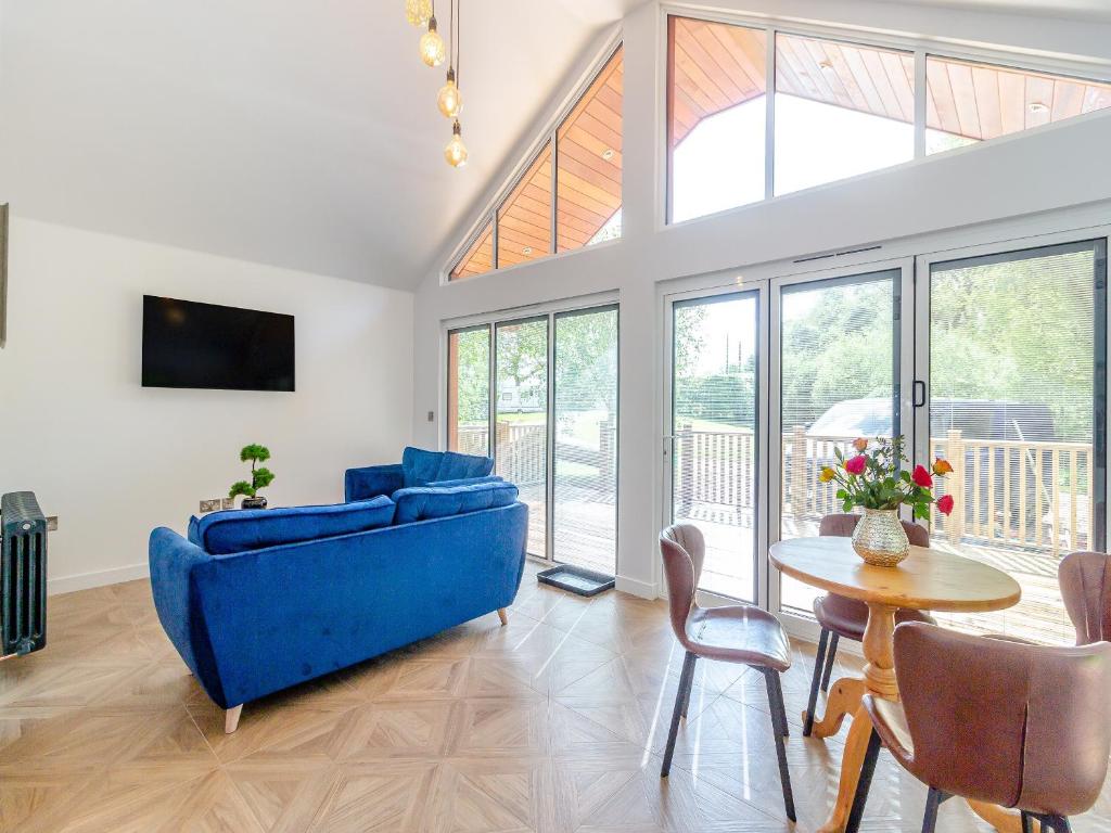 a living room with a blue couch and a table at Greenacres Cabin in Coleford