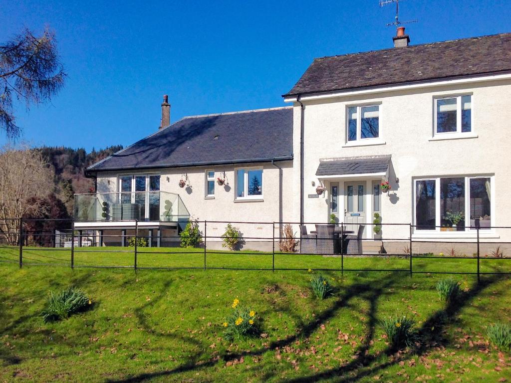 a white house with a fence in front of a yard at Teithbank in Callander