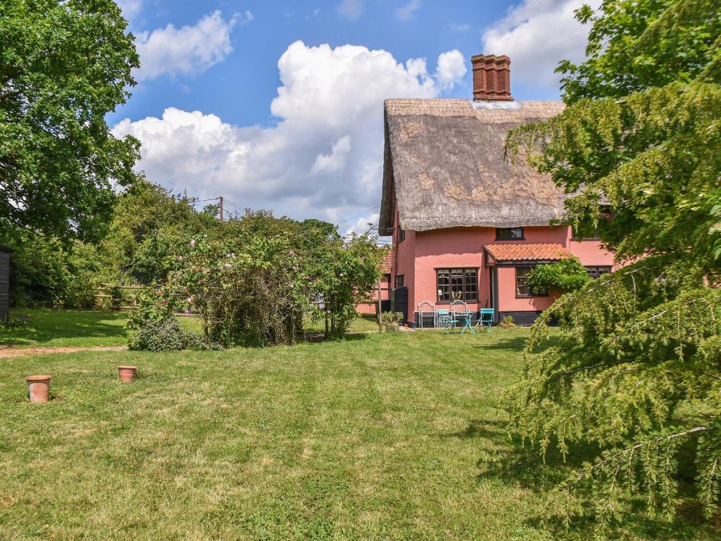 uma velha casa cor-de-rosa com um jardim de relva em Grove Cottage em Horham