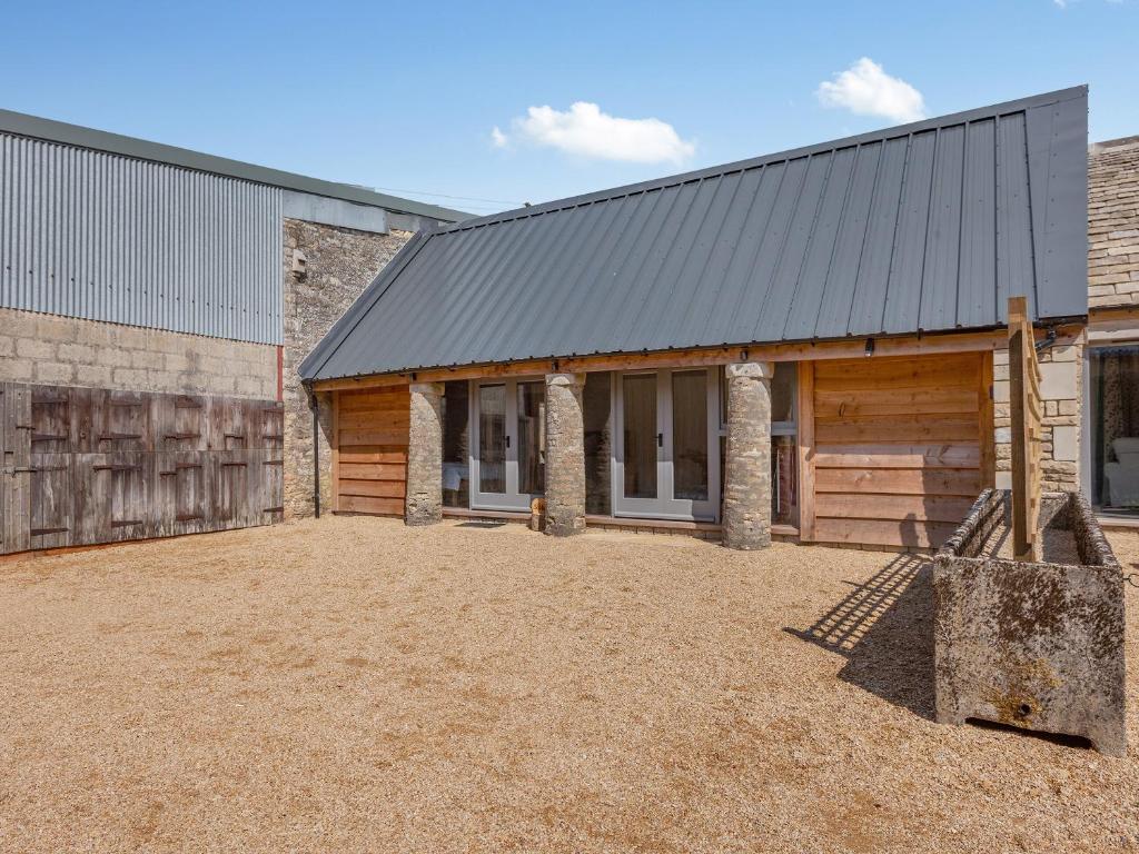 a barn with a metal roof and a building at The Stables - Uk44477 in Kingscote